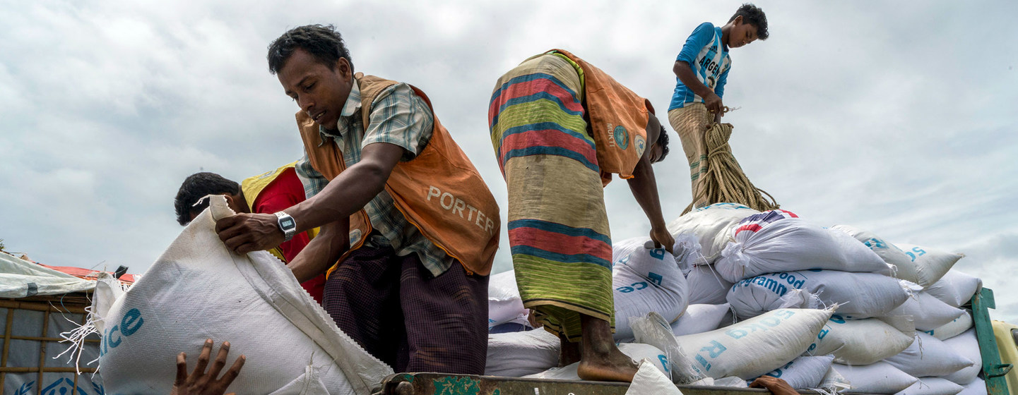 世界粮食计划署在孟加拉国的一个难民营的分发站，罗辛亚难民工人正在分发一袋袋大米和小扁豆。