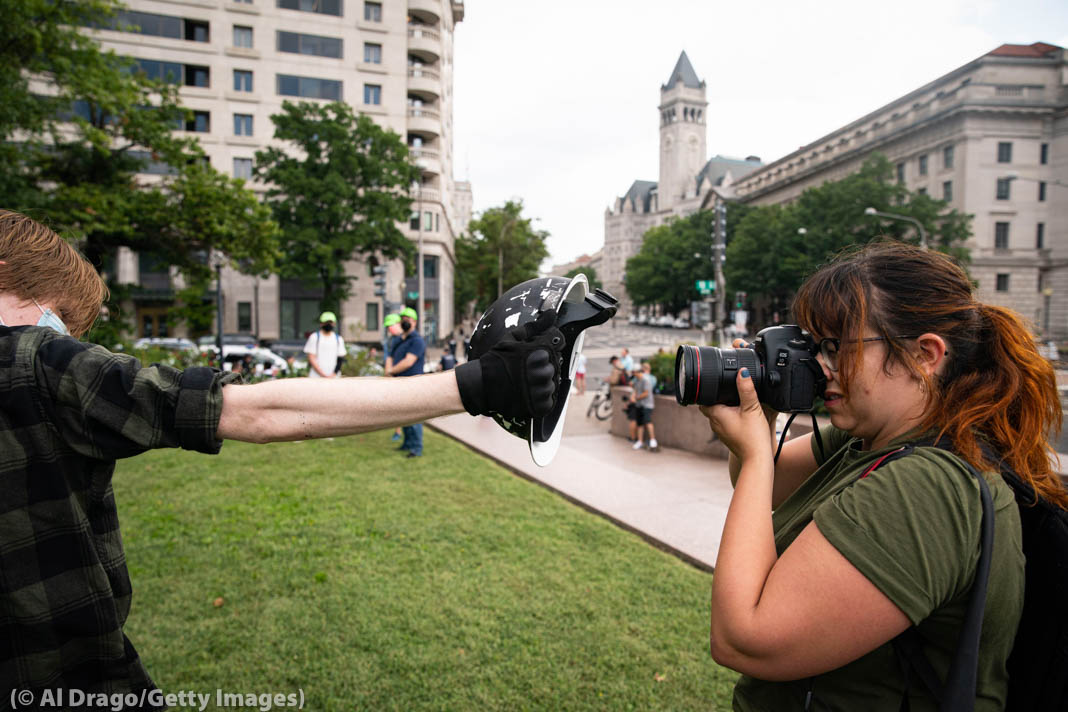 Protester holding up helmet to block camera of female photojournalist (© Al Drago/Getty Images)