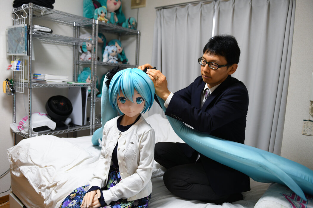 近藤明彦和虚拟流行歌星初音未来的玩偶在东京的家中。